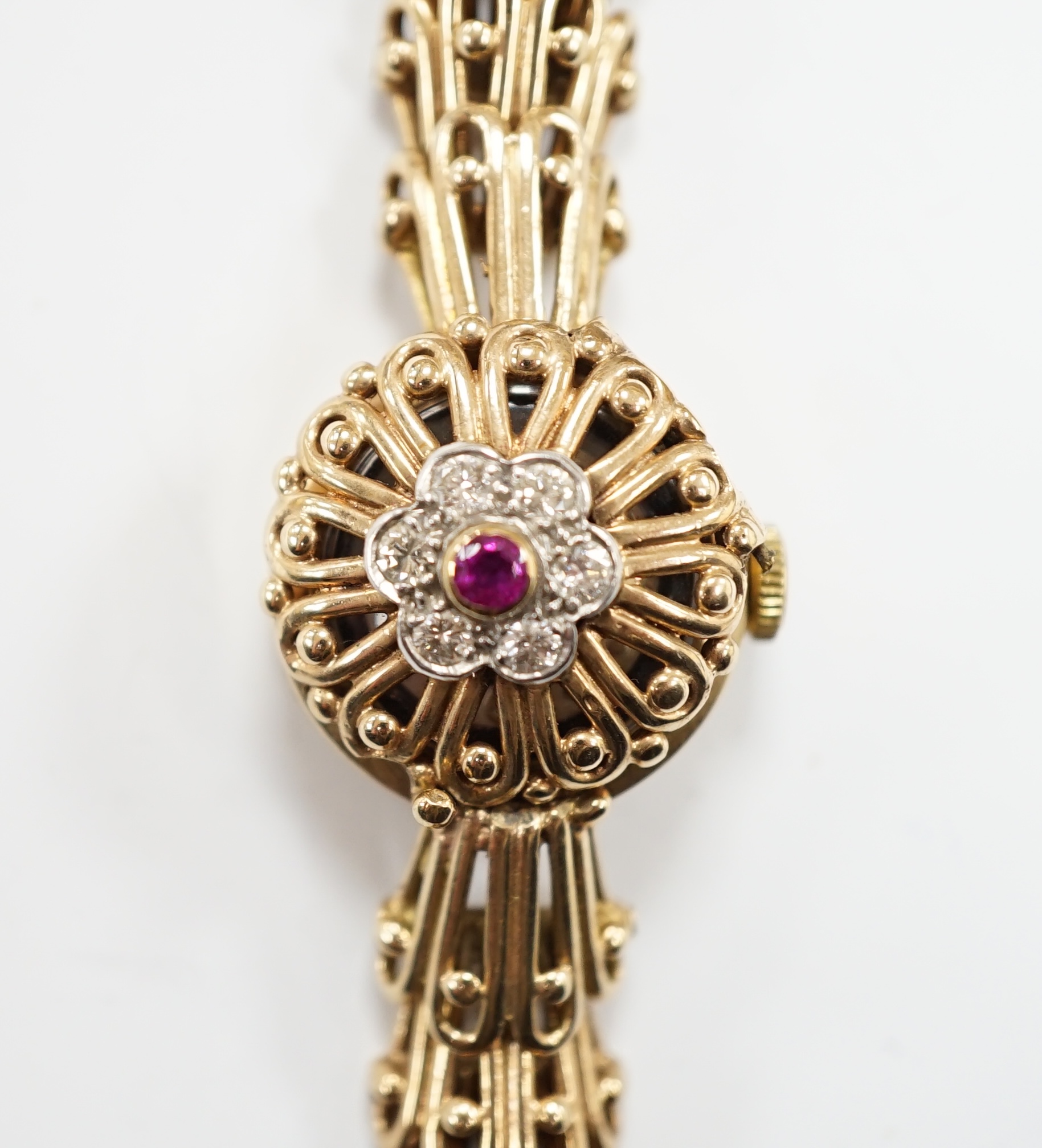 A lady's yellow metal manual wind bracelet watch, the dial with ruby and diamond cluster set hinged cover, overall length 16.3cm